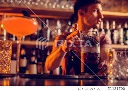 Dark-haired barman having night shift making cocktail Dark-haired barman having night shift making cocktail 51121700
