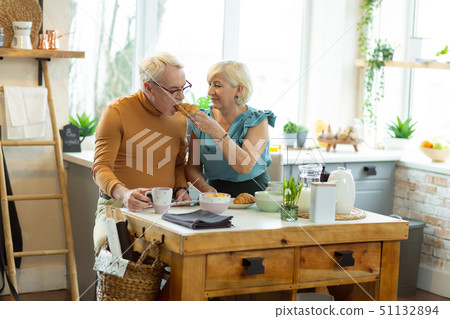 Glowing wife tenderly feeding up the old spouse with croissant 51132894