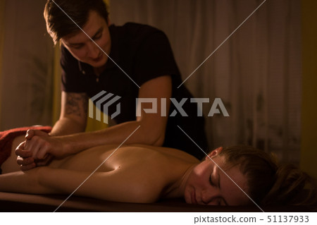 Masseur doing back massage for female client in spa center Masseur doing back massage for female client in spa center 51137933