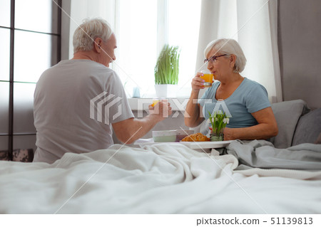 Happy spouses having breakfast in the bed and drinking juice Happy spouses having breakfast in the bed and drinking juice 51139813
