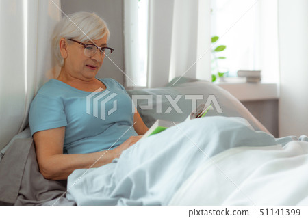 Charming lady lying in the bed and reading a book. 51141399