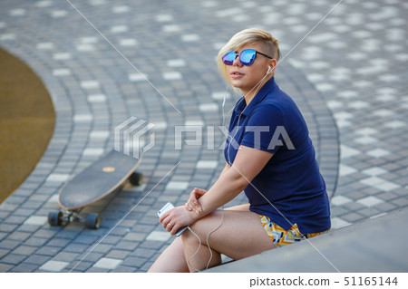 stylish girl in sunglasses listens to headphones 51165144