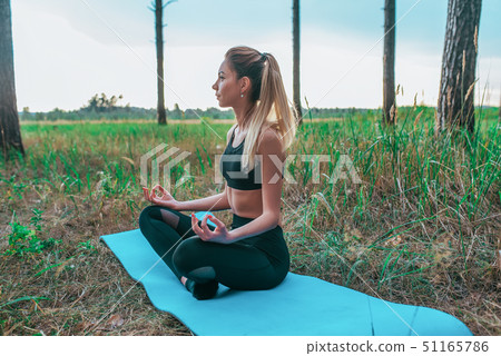 A girl sits on mat summer forest, meditates and concentrates practicing yoga, concept harmony of 51165786
