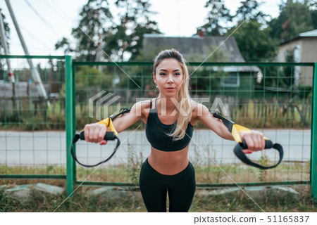 Female girl athlete training fitness workout in summer city. Rubber loop strap, push-up wiring hands 51165837