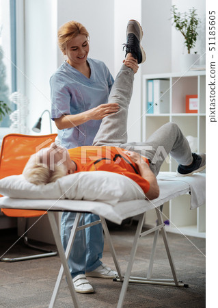 Nice pleasant woman looking at her patients leg Nice pleasant woman looking at her patients leg 51185605