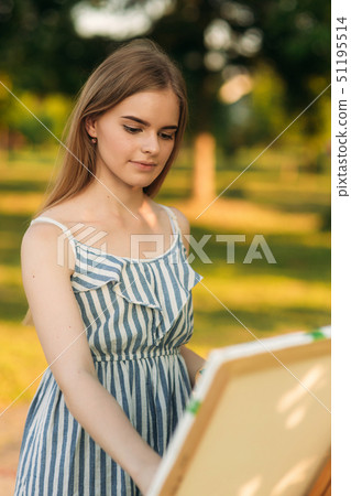 Portrait of Blond hair girl in dress drawing a picture in the park 51195514