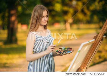 Portrait of Blond hair girl in dress drawing a picture in the park Portrait of Blond hair girl in dress drawing a picture in the park 51195561