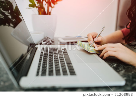 Woman hands writing in a small notepad. Laptop Woman hands writing in a small notepad. Laptop 51208998