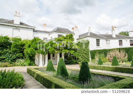 White-walled building with rattan shelf and a well-maintained garden In a park outside of England White-walled building with rattan shelf and a well-maintained garden In a park outside of England 51209628