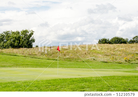 Golf course in early summer Green and fairway with red flag Golf course in early summer Green and fairway with red flag 51210579