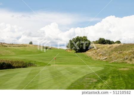 Golf course in early summer Green and fairway with red flag Golf course in early summer Green and fairway with red flag 51210582