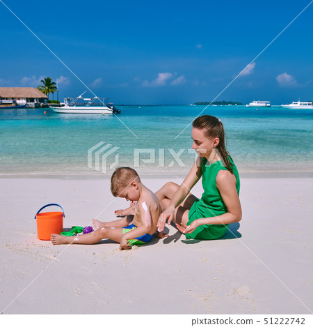 Woman applying sun screen on boy's back Woman applying sun screen on boy's back 51222742