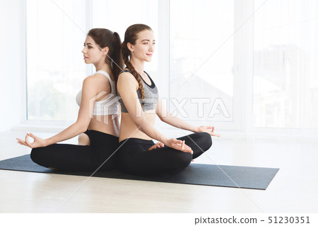 Two attractive women in sportswear on white background doing yoga Two attractive women in sportswear on white background doing yoga 51230351