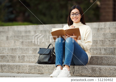 Happy Student Writing Notes In Notepad, Sitting On Stairs Happy Student Writing Notes In Notepad, Sitting On Stairs 51230402