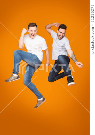 Two Friends Jumping And Celebrating Success Over Yellow Background 51236273