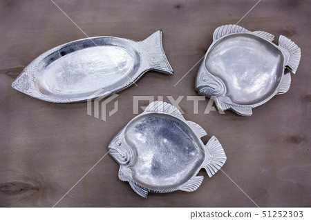 empty fish-shaped silver plates on a wooden table empty fish-shaped silver plates on a wooden table 51252303
