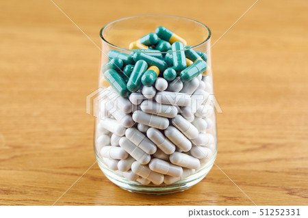 Many white and green pills in transparent glass Many white and green pills in transparent glass 51252331