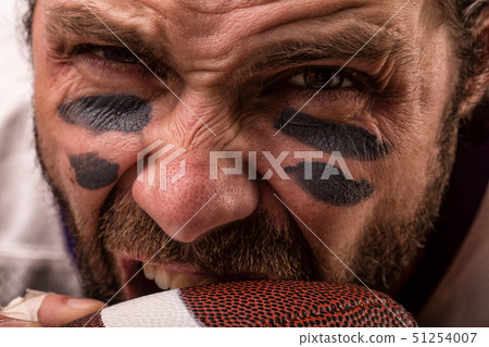 Close up portrait of aggressive American Football Player aggressive player biting his ball. 51254007