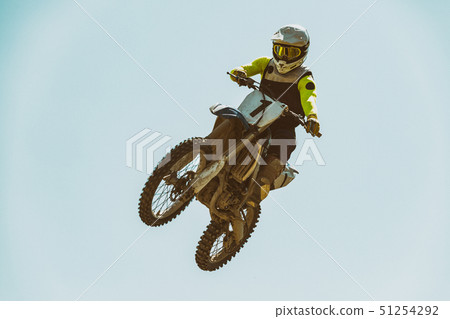 A picture of a biker making a stunt and jumps in the air A picture of a biker making a stunt and jumps in the air 51254292