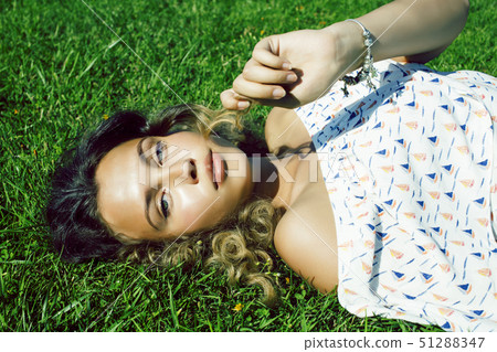 young pretty curly girl smiling cheerful on green grass, lifestyle people concept young pretty curly girl smiling cheerful on green grass, lifestyle people concept 51288347