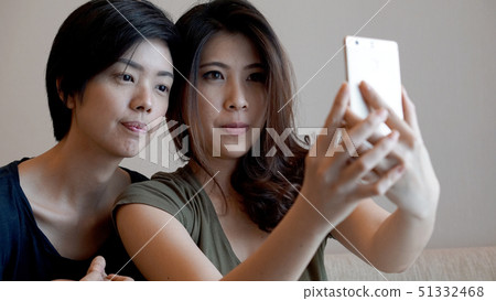 Two mixed race Asian girls taking selfie with smart phone Two mixed race Asian girls taking selfie with smart phone 51332468