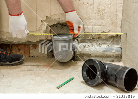 A worker is measuring the sewage drain pipe. A worker is measuring the sewage drain pipe. 51332819
