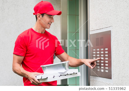 Pizza delivery man carrying boxes using the intercom Pizza delivery man carrying boxes using the intercom 51335962