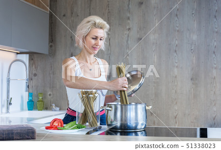 young blonde woman cooking in modern kitchen young blonde woman cooking in modern kitchen 51338023