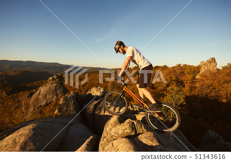 Male cyclist on trial bicycle on the top of boulder outdoors 51343616