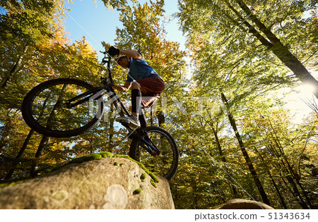 Sportsman cyclist balancing on back wheel on trial bicycle 51343634