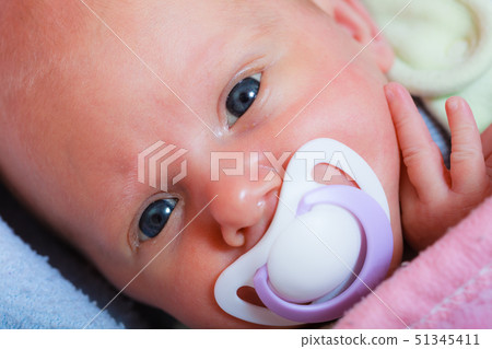 Newborn baby lying in bed with dummy Newborn baby lying in bed with dummy 51345411