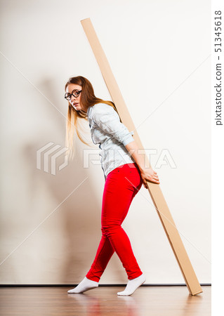 Woman moving into apartment carrying heavy box. 51345618