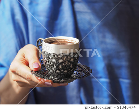 A cup of Turkish coffee holding women hands. A cup of Turkish coffee holding women hands. 51346474