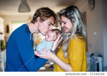 Beautiful young parents with a newborn baby at home, kissing. 51348189