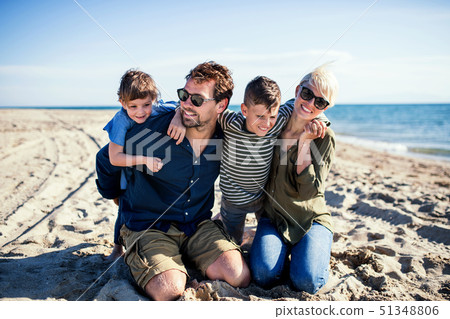 Young family with two small children sitting outdoors on beach. Young family with two small children sitting outdoors on beach. 51348806