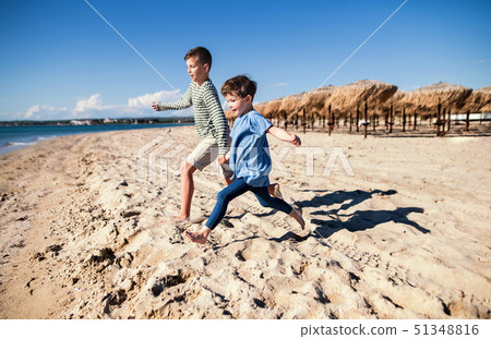Two small children running outdoors on sand beach. Two small children running outdoors on sand beach. 51348816