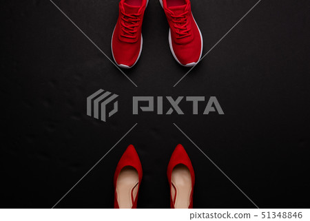 A studio shot of pair of running vs high heel shoes on black background. Flat lay. A studio shot of pair of running vs high heel shoes on black background. Flat lay. 51348846