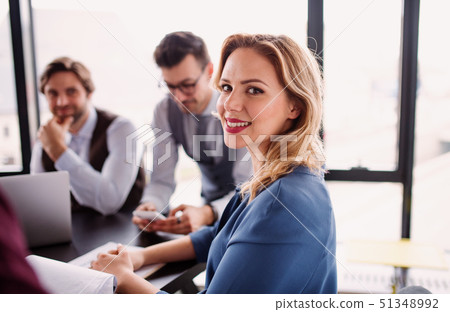 A group of young business people with laptop sitting in an office, talking. 51348992