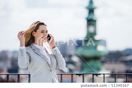 A young businesswoman with smartphone standing on a terrace, working. 51349167