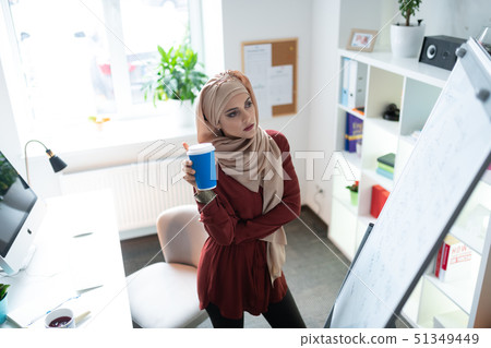 Teacher drinking takeaway coffee and looking at whiteboard 51349449