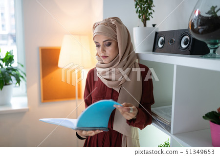 Appealing teacher wearing headscarf reading some papers 51349653