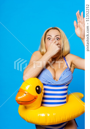 Photo of young blonde in striped swimsuit with lifeline at waist covering her nose with her hand 51352252