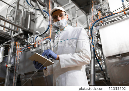man in a white robe and a cap make an inspection of the production line 51353302
