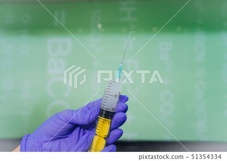 Hands in rubber gloves hold a disposable medical syringe with the drug 51354334
