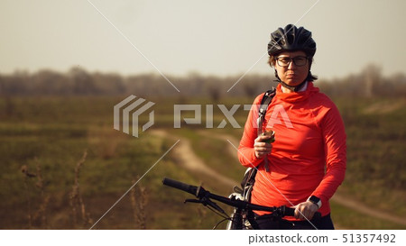 Athletic Caucasian woman eats protein bar ride on mountain bike on nature. Young sporty woman 51357492