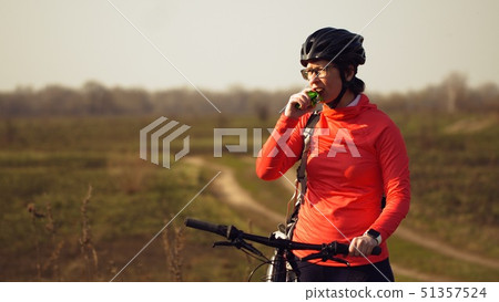 Athletic Caucasian woman eats protein bar ride on mountain bike on nature. Young sporty woman 51357524