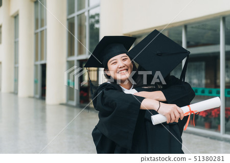 Graduates in mantles with diplomas hugging Graduates in mantles with diplomas hugging 51380281