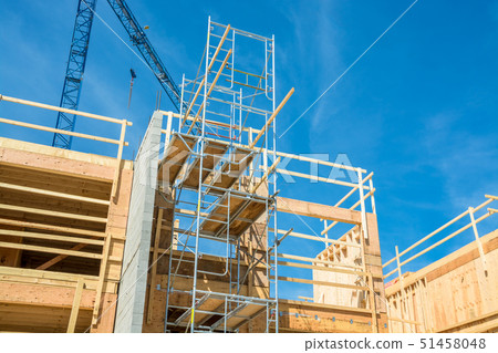 Scaffolding for construction of new low-rise building with crane above the site. 51458048