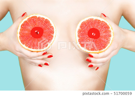 Sexy young woman holding grapefruits near her breasts on color background. 51700059