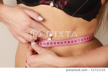 Woman measuring her waist closeup Woman measuring her waist closeup 51721135